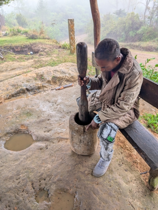 Daniel grinding coffee in a traditional pilon