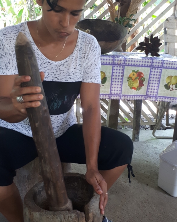 Grinding her cacao in a pilon